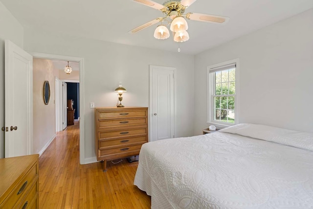 bedroom with light wood-type flooring, baseboards, and ceiling fan