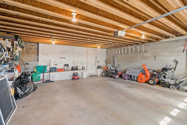 garage featuring a garage door opener and concrete block wall