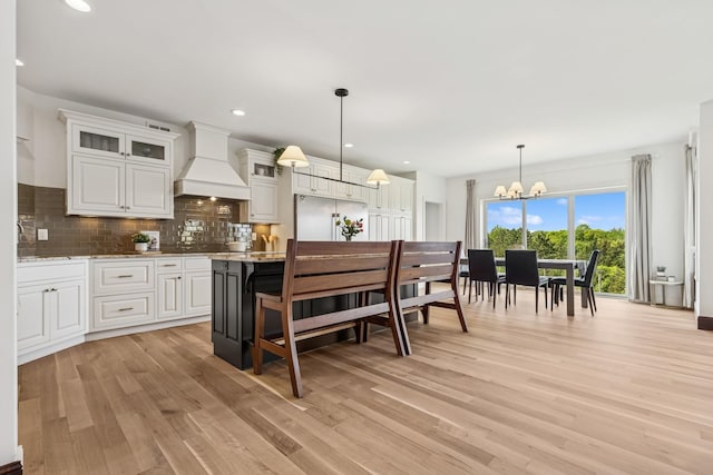2169 Ibson Ave SE, Rockford Twp, MN 55313 - kitchen with custom exhaust hood, a chandelier, light wood-style floors, decorative backsplash, and white cabinets