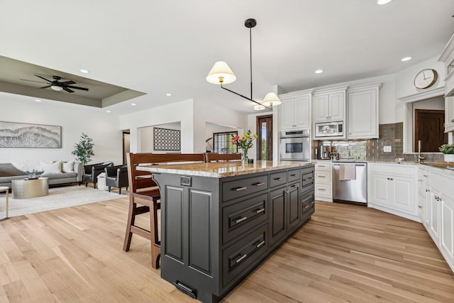 2169 Ibson Ave SE, Rockford Twp, MN 55313 - kitchen featuring appliances with stainless steel finishes, white cabinetry, a kitchen breakfast bar, light wood-type flooring, and recessed lighting