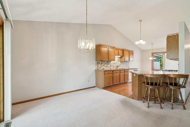 2558 75th St E, Inver Grove Heights, MN 55076 - kitchen with light colored carpet, a chandelier, lofted ceiling, dishwasher, and brown cabinets