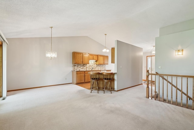 2558 75th St E, Inver Grove Heights, MN 55076 - kitchen with a breakfast bar, light colored carpet, a chandelier, backsplash, and high vaulted ceiling
