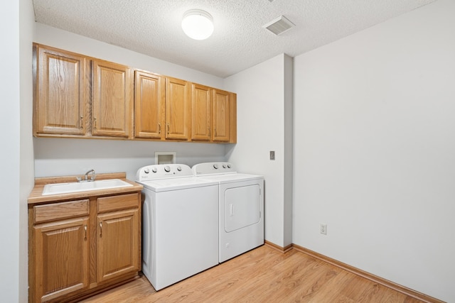 2558 75th St E, Inver Grove Heights, MN 55076 - laundry area featuring cabinet space, washing machine and clothes dryer, light wood finished floors, and a textured ceiling