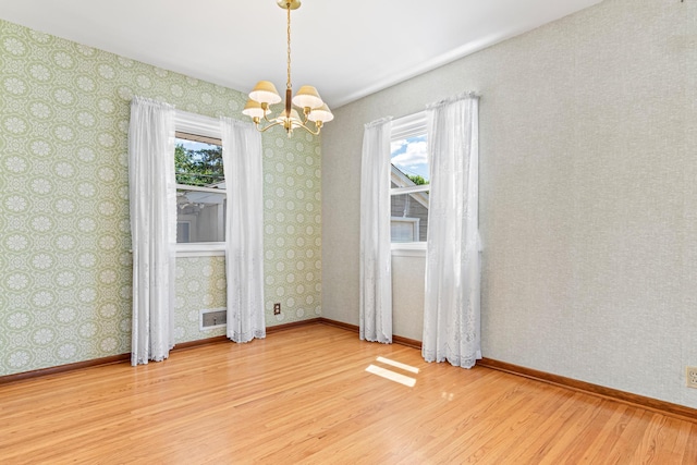 7109 Penn Ave S, Richfield, MN 55423 - spare room with wood finished floors, plenty of natural light, a chandelier, baseboards, and wallpapered walls