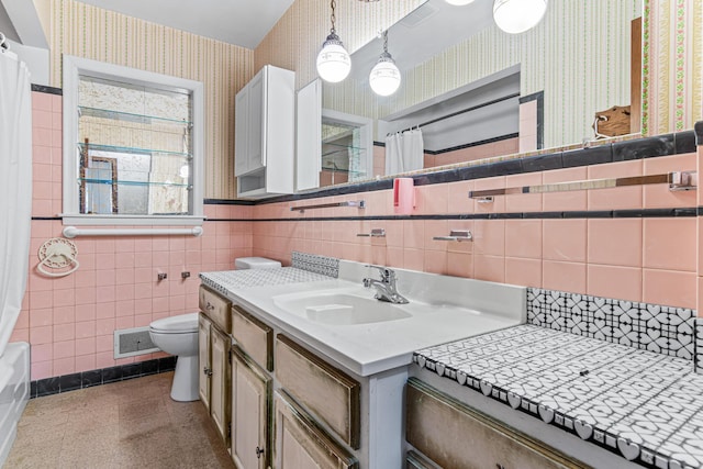 7109 Penn Ave S, Richfield, MN 55423 - bathroom with wallpapered walls, toilet, vanity, a wainscoted wall, and tile walls