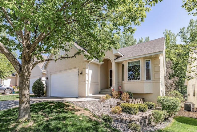 view of front facade featuring central AC, a garage, stucco siding, driveway, and roof with shingles