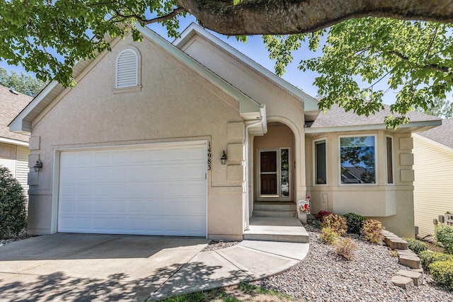 view of front facade with a garage, concrete driveway, stucco siding, and roof with shingles