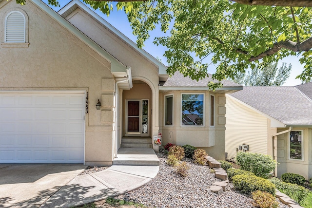 entrance to property featuring a garage, stucco siding, and concrete driveway