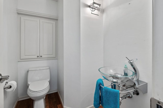 half bath with wood finished floors, toilet, and baseboards