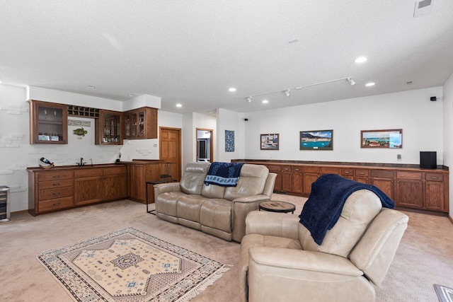 living area featuring light carpet, recessed lighting, wet bar, and a textured ceiling