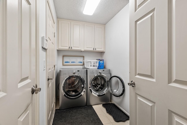 washroom featuring washer and clothes dryer, a textured ceiling, cabinet space, light tile patterned floors, and baseboards