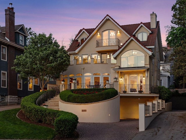 2683 Lake Of The Isles Pkwy, Minneapolis, MN 55408 - back of house featuring a balcony, a chimney, driveway, stucco siding, and a tiled roof
