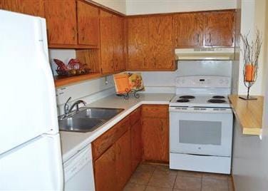 7673 River Rd, Fridley, MN 55432 - kitchen with white appliances, under cabinet range hood, a sink, brown cabinetry, and light tile patterned floors