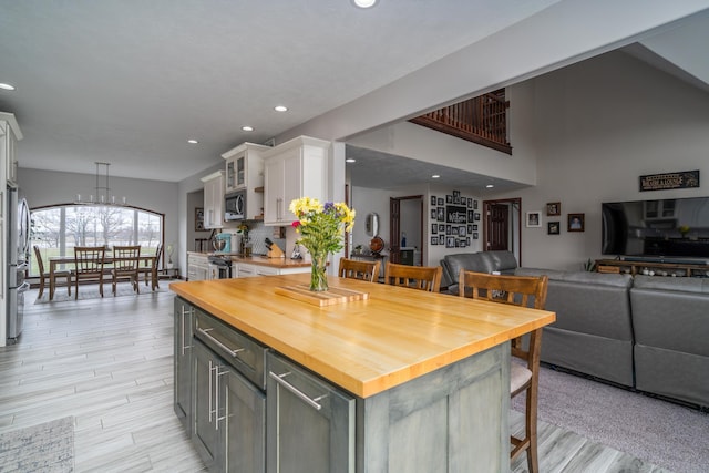 37854 210th Ave SE, Knute Twp, MN 56535 - kitchen featuring butcher block countertops, white cabinets, open floor plan, a kitchen bar, and stainless steel appliances