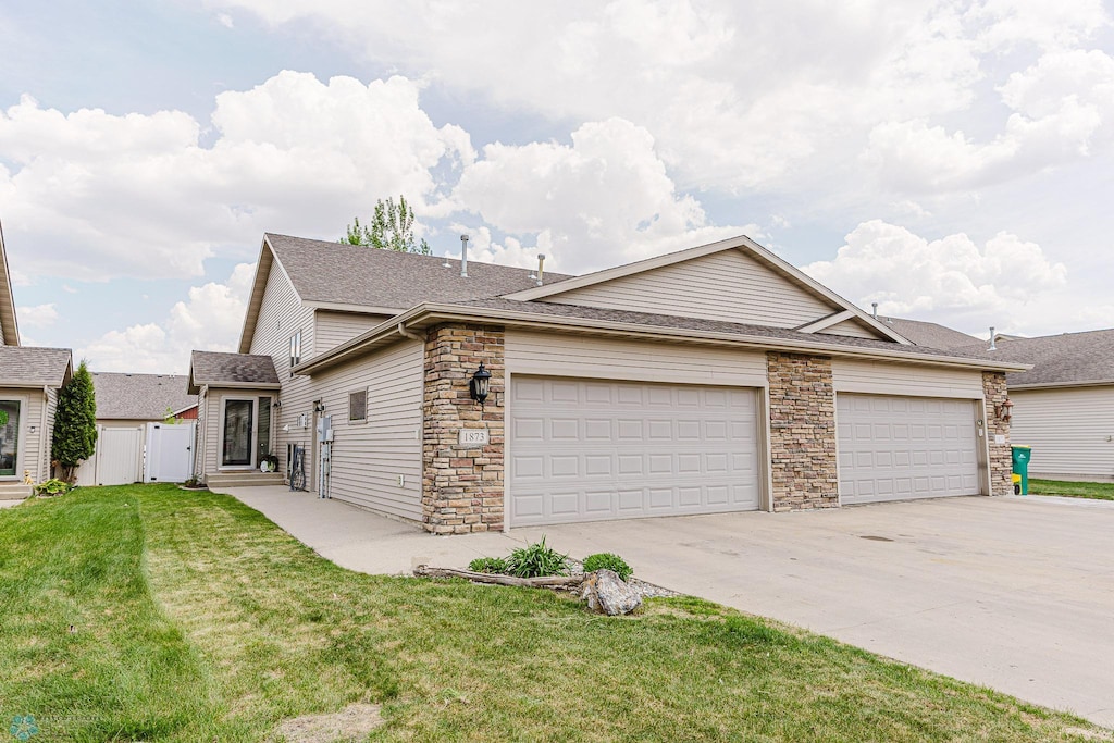 1873 6th St W, West Fargo, ND 58078 - view of front of home featuring driveway, a garage, stone siding, roof with shingles, and a gate