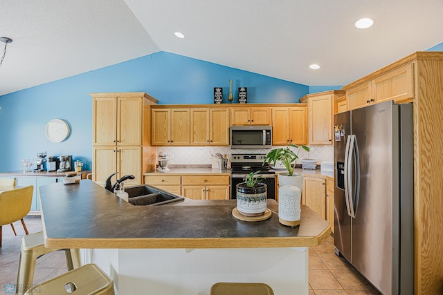 kitchen with stainless steel appliances, a sink, lofted ceiling, a kitchen bar, and backsplash