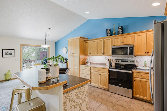 kitchen featuring stainless steel appliances, vaulted ceiling, a kitchen breakfast bar, tasteful backsplash, and decorative light fixtures