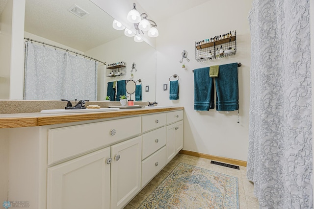 full bath with double vanity, tile patterned floors, and baseboards