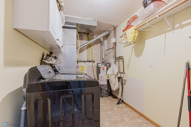 laundry area with water heater, washing machine and clothes dryer, cabinet space, and baseboards