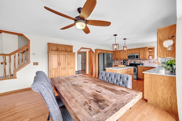 13883 Holly St NW, Andover, MN 55304 - dining space featuring light wood-style floors, a ceiling fan, stairway, and baseboards