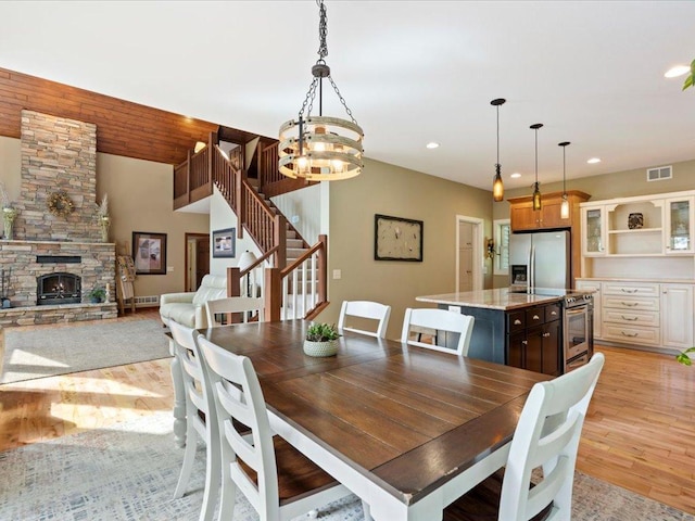26746 County Road 4, Nisswa, MN 56468 - dining room with light wood-style floors, a chandelier, recessed lighting, a fireplace, and stairs