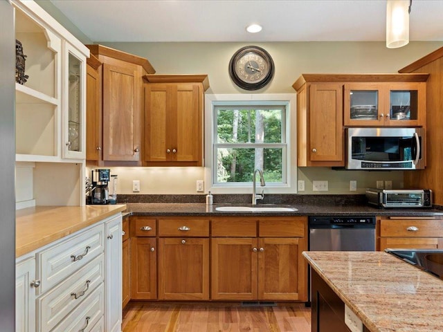 26746 County Road 4, Nisswa, MN 56468 - kitchen featuring appliances with stainless steel finishes, a sink, brown cabinets, dark stone countertops, and recessed lighting
