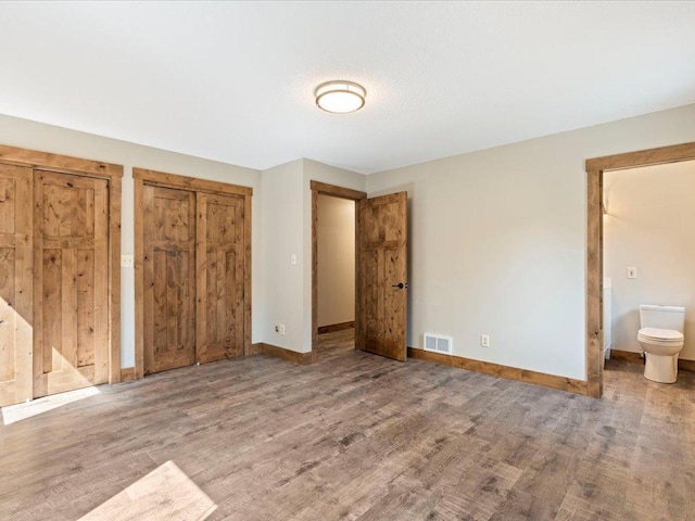 26746 County Road 4, Nisswa, MN 56468 - unfurnished bedroom with baseboards, wood finished floors, multiple closets, and ensuite bathroom