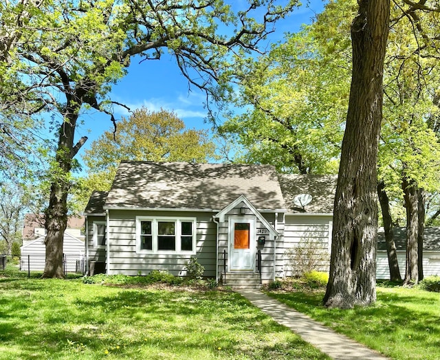 view of front of home with a front lawn and a shingled roof