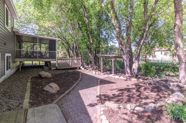 view of yard with a sunroom, a deck, and fence