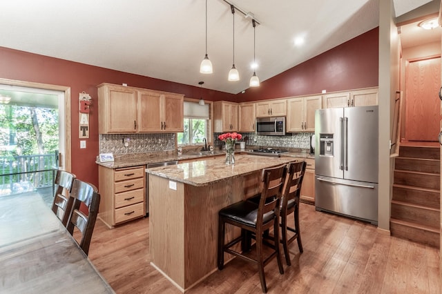 kitchen with appliances with stainless steel finishes, light wood-style flooring, decorative backsplash, vaulted ceiling, and light stone countertops