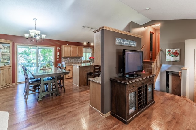 kitchen with a chandelier, wood finished floors, decorative backsplash, lofted ceiling, and decorative light fixtures