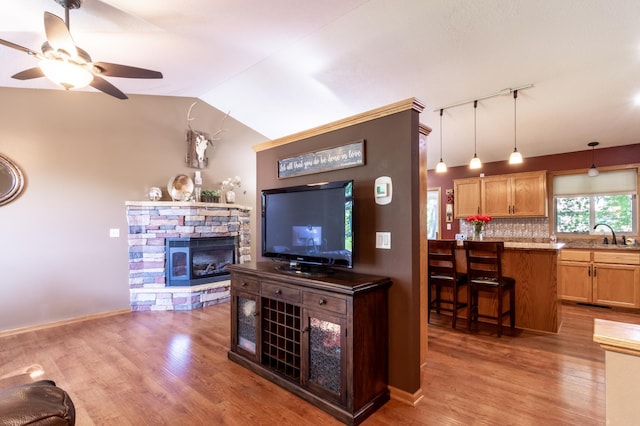 living area featuring ceiling fan, wood finished floors, a fireplace, lofted ceiling, and rail lighting