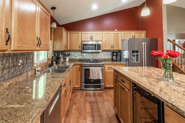 kitchen featuring appliances with stainless steel finishes, a sink, wine cooler, vaulted ceiling, and light wood-style flooring