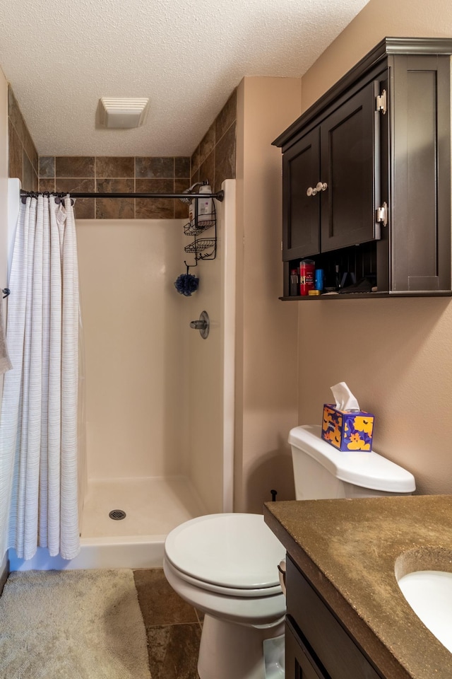 bathroom featuring a shower stall, toilet, a textured ceiling, and vanity