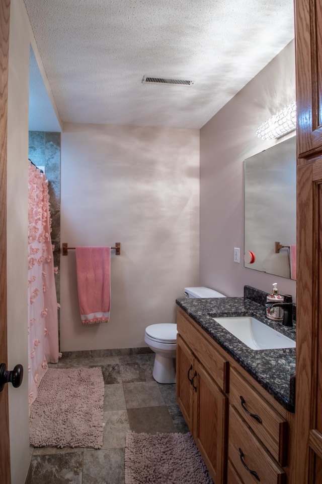 bathroom with toilet, vanity, a textured ceiling, and a shower with curtain