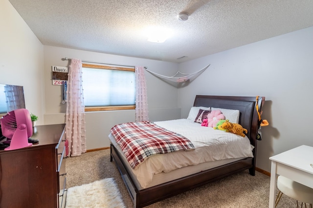 bedroom featuring light carpet, baseboards, and a textured ceiling