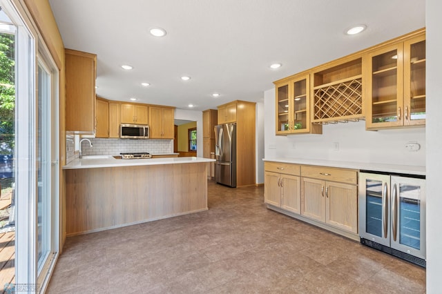 kitchen featuring appliances with stainless steel finishes, beverage cooler, light countertops, glass insert cabinets, and a peninsula