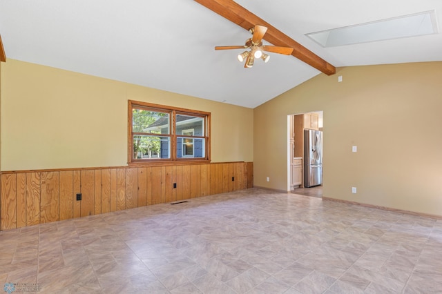 unfurnished room with ceiling fan, wooden walls, and a wainscoted wall