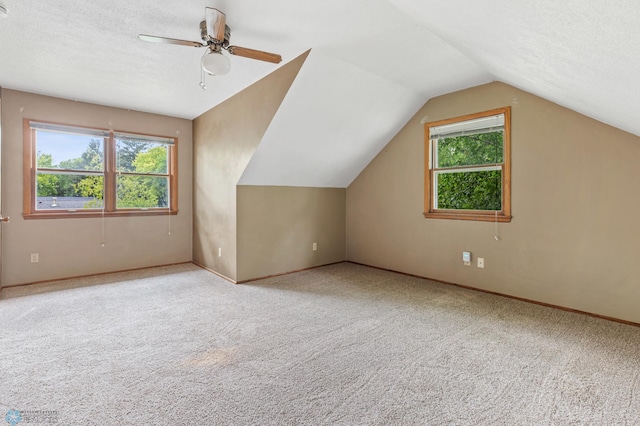 additional living space featuring carpet flooring, lofted ceiling, ceiling fan, baseboards, and a textured ceiling