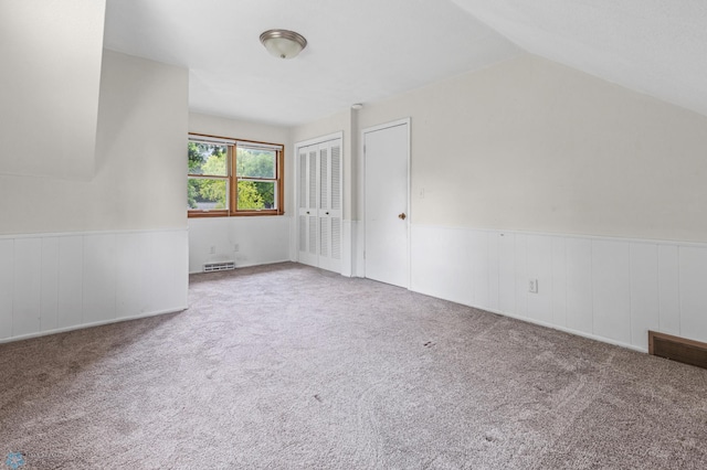 additional living space with wainscoting, carpet flooring, and lofted ceiling