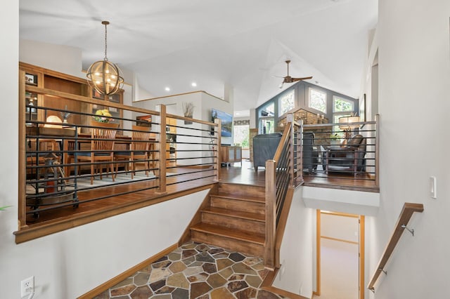 stairs with lofted ceiling, ceiling fan, a chandelier, and stone finish flooring