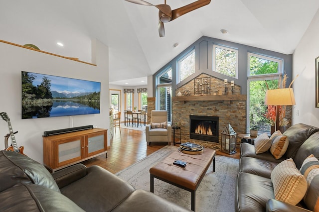 living area featuring wood finished floors, a ceiling fan, a stone fireplace, high vaulted ceiling, and recessed lighting