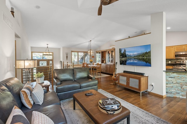 living room featuring wood finished floors, ceiling fan, a chandelier, and vaulted ceiling