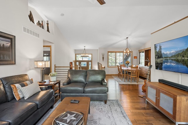living room with a chandelier, vaulted ceiling, and dark wood-style floors