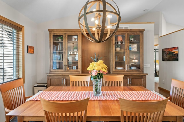 dining room featuring lofted ceiling, a chandelier, baseboards, and wood finished floors