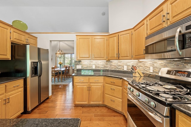 kitchen featuring appliances with stainless steel finishes, tasteful backsplash, light wood finished floors, and a chandelier