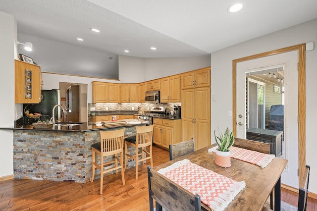 dining space with vaulted ceiling, light wood-style flooring, and recessed lighting