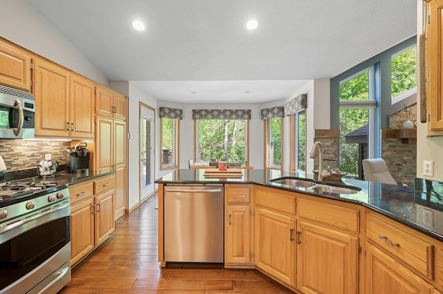 kitchen featuring stainless steel appliances, a sink, healthy amount of natural light, dark stone countertops, and recessed lighting