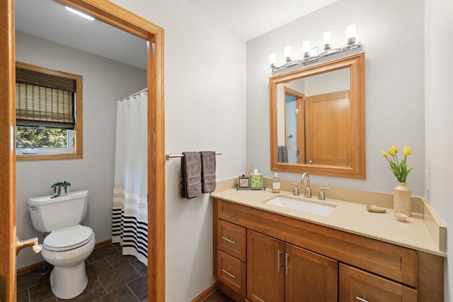 full bathroom featuring toilet, vanity, baseboards, and stone finish floors