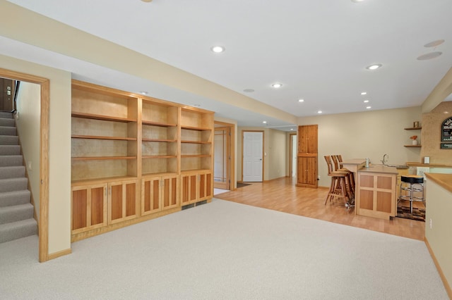 office area featuring bar with sink, recessed lighting, light carpet, light wood-style flooring, and baseboards